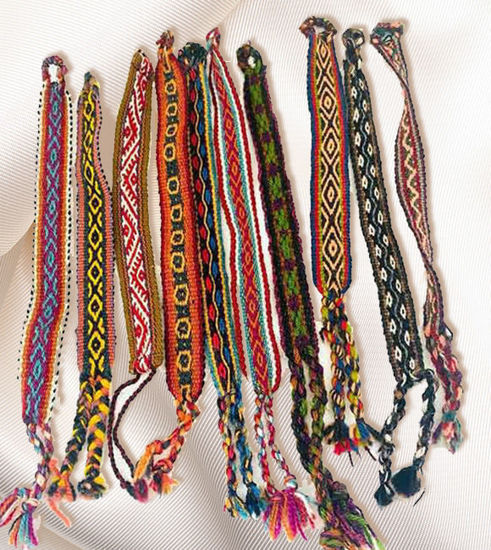 Vibrant handmade bracelets made from Peruvian manta fabric, displayed on white cloth, featuring unique Inca patterns.