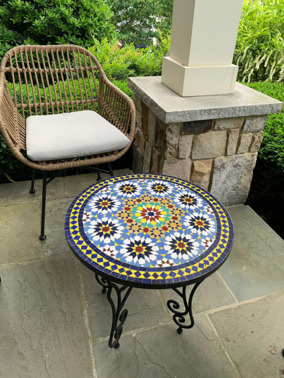 A colorful Moroccan mosaic table on a patio, showcasing intricate patterns and vibrant tiles, perfect for indoor or outdoor use.