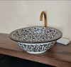 Black and white ceramic wash basin with a gold faucet, showcasing Moroccan craftsmanship and elegant design for bathrooms.