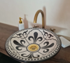 Black and white ceramic bathroom sink with a gold faucet, showcasing traditional Moroccan design and craftsmanship.