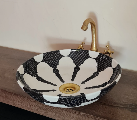 Black and white ceramic vessel sink with a gold faucet, showcasing intricate Moroccan hand-painted designs and craftsmanship.
