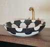 Hand-painted black and white ceramic sink bowl with a gold faucet, reflecting traditional Moroccan design and craftsmanship.