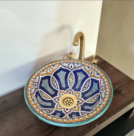 Decorative ceramic vessel sink with a gold faucet, featuring a hand-painted blue and white mandala design.