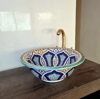 Handcrafted ceramic sink with a gold faucet, adorned with intricate blue and white mandala designs, perfect for any bathroom.