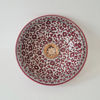 A decorative red and white bowl adorned with floral motifs, exemplifying Moroccan ceramic artistry and mid-century design.