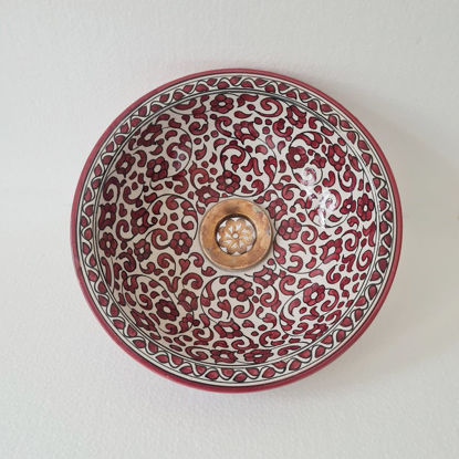 A decorative red and white bowl adorned with floral motifs, exemplifying Moroccan ceramic artistry and mid-century design.