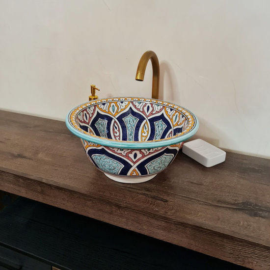Colorful handmade Moroccan ceramic bowl on a wooden counter, showcasing intricate patterns and vibrant Mediterranean design.