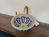 Vibrant Moroccan ceramic bowl resting on a wooden counter, featuring intricate hand-painted designs and Mediterranean charm.