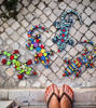 A person's feet beside vibrant, handcrafted mosaic lizards, showcasing colorful ceramic tiles and unique designs.