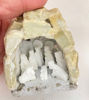 A hand holds a small white stone nativity scene featuring the Holy Family in a rustic grotto, showcasing Peruvian craftsmanship.