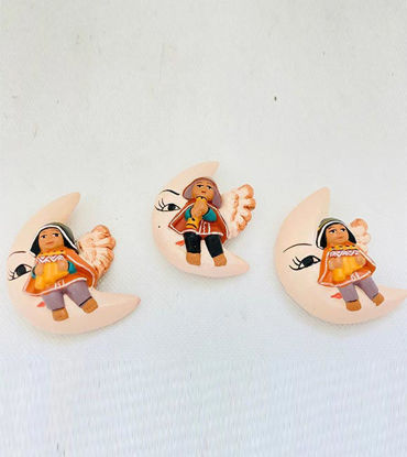 A crescent moon holds three small ceramic dolls, featuring an angel and moon designs, beautifully hand-painted by artisans.