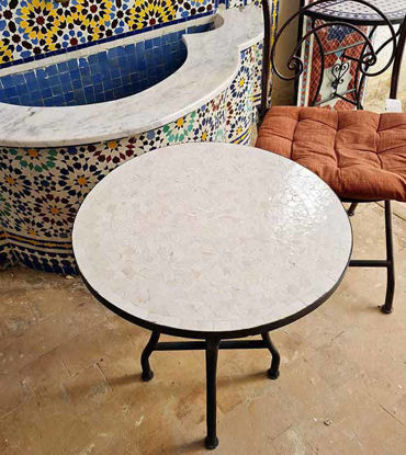 Handmade round white mosaic table with vibrant designs, paired with a chair, perfect for outdoor gatherings.