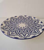 A decorative 14-inch ceramic plate, hand-painted in blue and white Moroccan patterns, showcasing artisan craftsmanship.