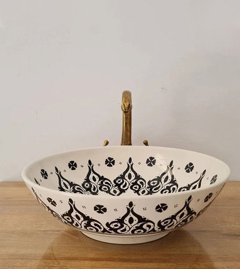 Black and white Moroccan ceramic sink with a gold handle, showcasing mid-century modern design and intricate patterns.