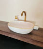 White bathroom sink with pink accents and a gold faucet, showcasing mid-century Moroccan craftsmanship and elegant design.