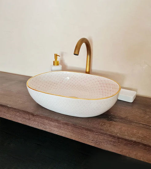 White bathroom sink with pink accents and a gold faucet, showcasing mid-century Moroccan craftsmanship and elegant design.