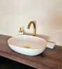 Elegant white sink with pink details and a gold faucet, highlighting handcrafted Moroccan artistry in a modern bathroom setting.