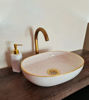 Luxurious white bathroom sink featuring pink accents and a gold faucet, embodying mid-century Moroccan design and craftsmanship.
