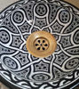 Hand-painted black and white terracotta sink with a gold handle, showcasing intricate Moroccan patterns and Mediterranean charm.