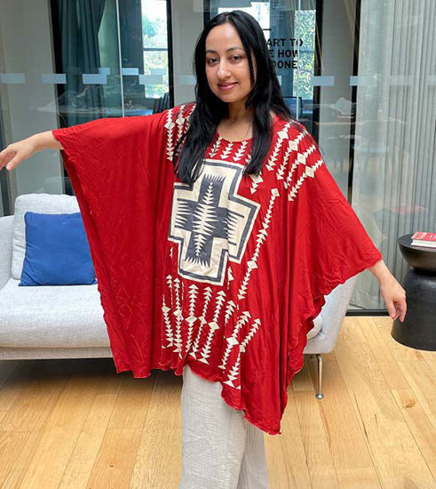 A woman in a flowing red poncho, embodying the cultural pride and bohemian spirit of the Wildflower Breeze Kaftan top.