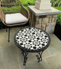 Round black and white mosaic table on a patio, featuring handcrafted Moroccan Zellige tiles that enhance outdoor decor.