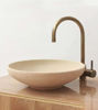 Round ceramic sink in white with a brass faucet, highlighting detailed Moroccan craftsmanship and a timeless patina finish.