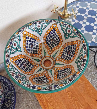 Show details for Customizable Moroccan Ceramic Vessel Sink – Hand-Painted Bathroom Drop-In Basin | Artisan Ceramic Bowl for Bathroom Remodeling A vibrant, hand-painted Moroccan ceramic vessel sink displayed on a table, showcasing intricate patterns and rich colors.