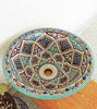 A vibrant ceramic sink bowl with intricate Moroccan patterns, resting on a wooden table, highlighting its artistic craftsmanship.