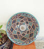 Handcrafted Moroccan ceramic bowl with colorful designs, placed on a wooden table, emphasizing its unique artistry and charm.