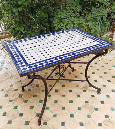 A blue and white Moroccan mosaic tile table on a patio, showcasing intricate patterns and a low rectangular design.