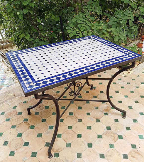 A blue and white Moroccan mosaic tile table on a patio, showcasing intricate patterns and a low rectangular design.