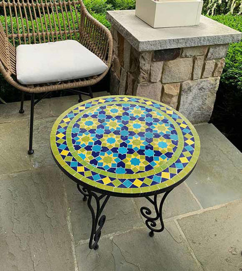 Colorful Moroccan mosaic table featuring intricate red and yellow patterns, placed on a sunny patio, enhancing the outdoor decor.