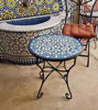 Colorful handmade Moroccan mosaic tile on a round coffee table, showcasing intricate blue patterns and artisan craftsmanship.