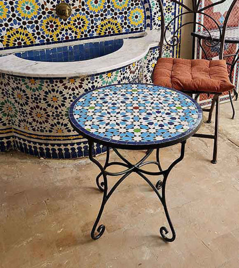 Colorful handmade Moroccan mosaic tile on a round coffee table, showcasing intricate blue patterns and artisan craftsmanship.
