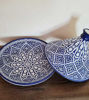 Handmade Moroccan tagine pot in blue and white ceramic, displayed on a wooden table, showcasing intricate geometric designs.