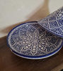 Elegant blue and white ceramic tagine pot resting on a wooden table, featuring unique hand-painted Moroccan patterns.