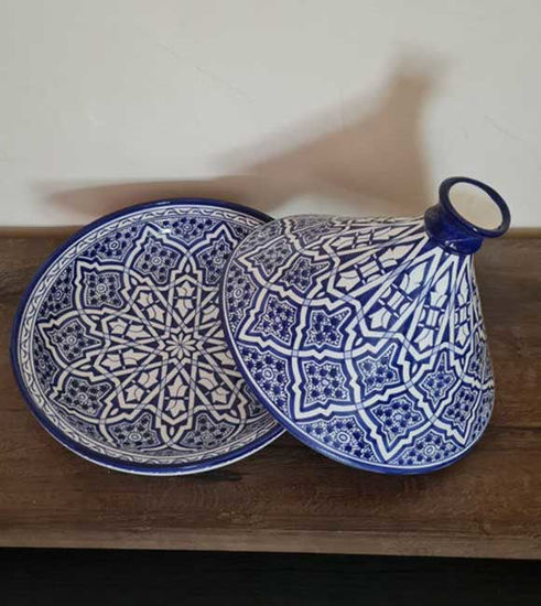 Large blue and white ceramic tagine pot on a wooden table, highlighting traditional Moroccan craftsmanship and design.