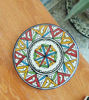 Artisanal Moroccan ceramic coaster arranged on a wooden table, highlighting its colorful hand-painted details and stone-style finish.
