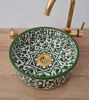 A handmade green and gold Moroccan ceramic sink with intricate patterns and a gold faucet, showcasing traditional craftsmanship.
