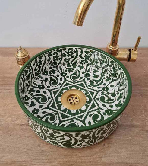 A handmade green and gold Moroccan ceramic sink with intricate patterns and a gold faucet, showcasing traditional craftsmanship.