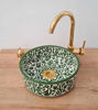 A vibrant green and gold ceramic sink featuring a gold faucet, highlighting authentic Moroccan artistry and unique design.