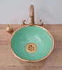 Green ceramic sink with an aged brass rim and faucet, showcasing Moroccan craftsmanship and unique artisanal details.