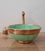 Handmade green ceramic sink with a brushed brass rim and faucet, reflecting traditional Moroccan design and durability.