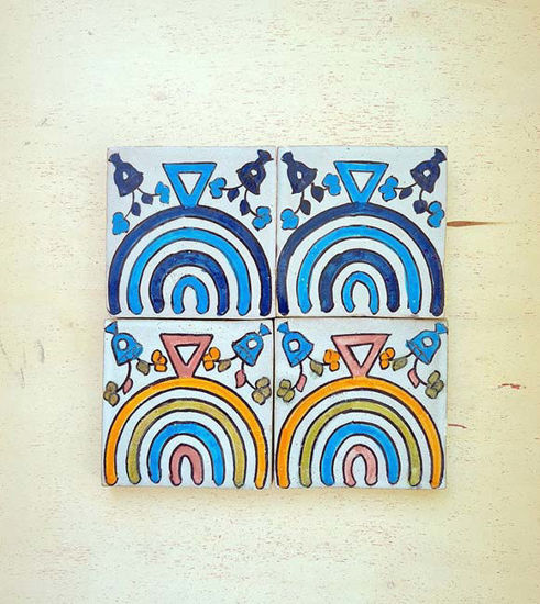 Four hand-painted terracotta tiles featuring vibrant rainbow designs, showcasing Moroccan craftsmanship and unique artistry.