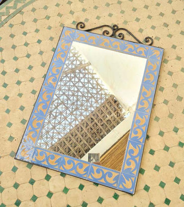 Light blue Moroccan mosaic mirror on a tiled floor, showcasing intricate geometric patterns and handcrafted artistry.