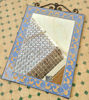 Handmade light blue mosaic mirror with geometric designs, placed on a tiled floor, reflecting Moroccan craftsmanship.