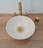 A white ceramic vessel sink with a gold faucet, showcasing minimalist hand-painted design, perfect for modern bathrooms.