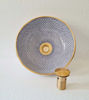 Blue and white porcelain bowl with a gold handle, showcasing intricate patterns and Moroccan craftsmanship.