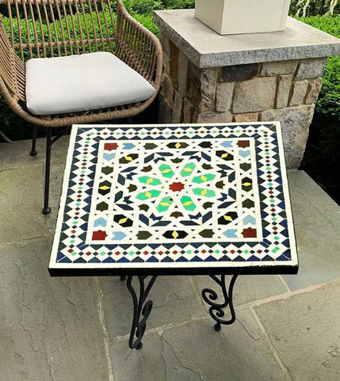 Colorful handmade mosaic table on a patio, showcasing Moroccan artistry with customizable design options for indoor or outdoor use.