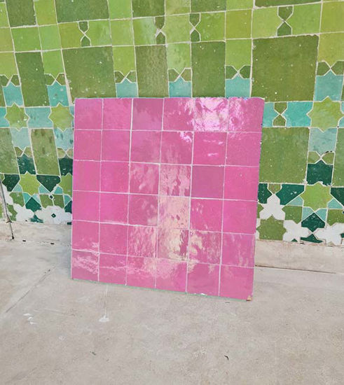 Rose pink tile flooring in front of a green and white tiled wall, highlighting unique handmade Moroccan Zellige artistry.